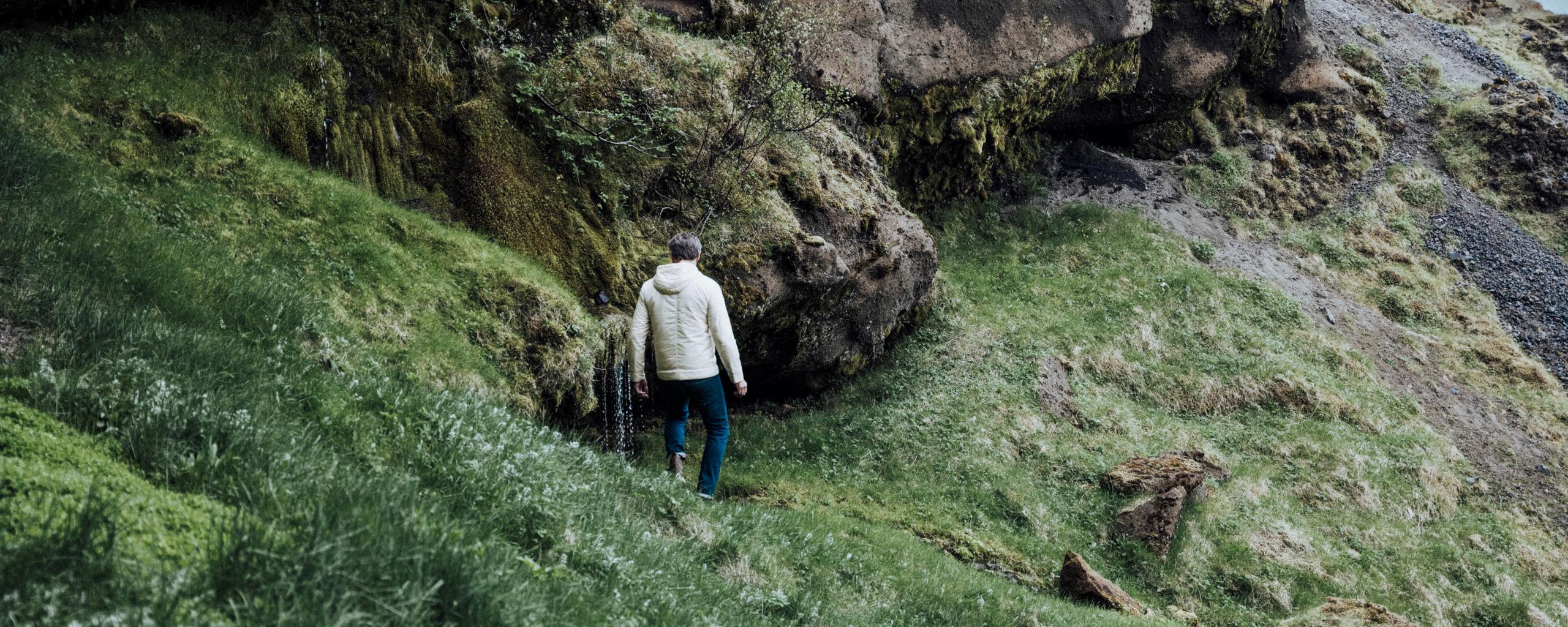Man walking down green hillside in Iceland