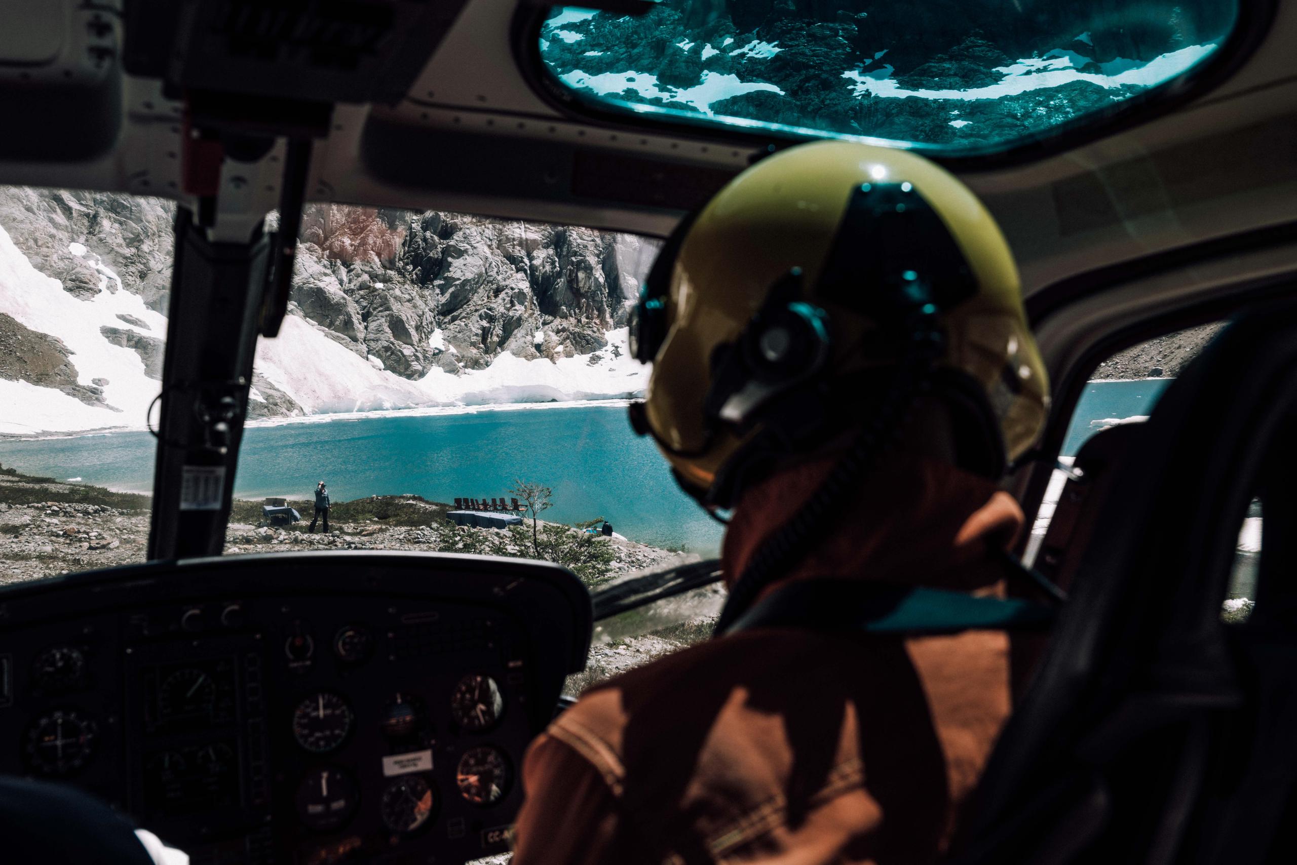 Inside helicopter view of pilot overlooking lake in Patagonia