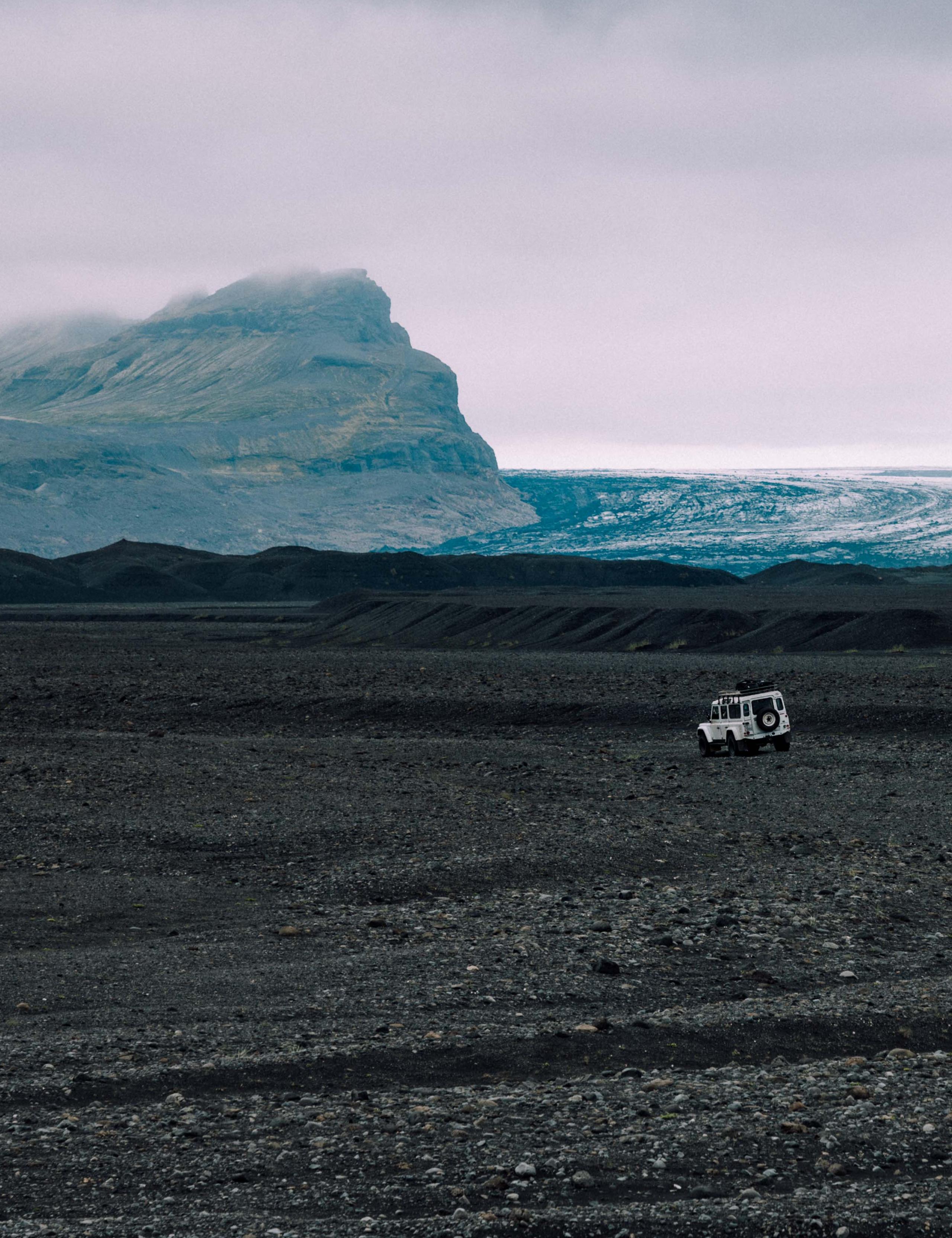 White Defender driving on black sand beach in Iceland
