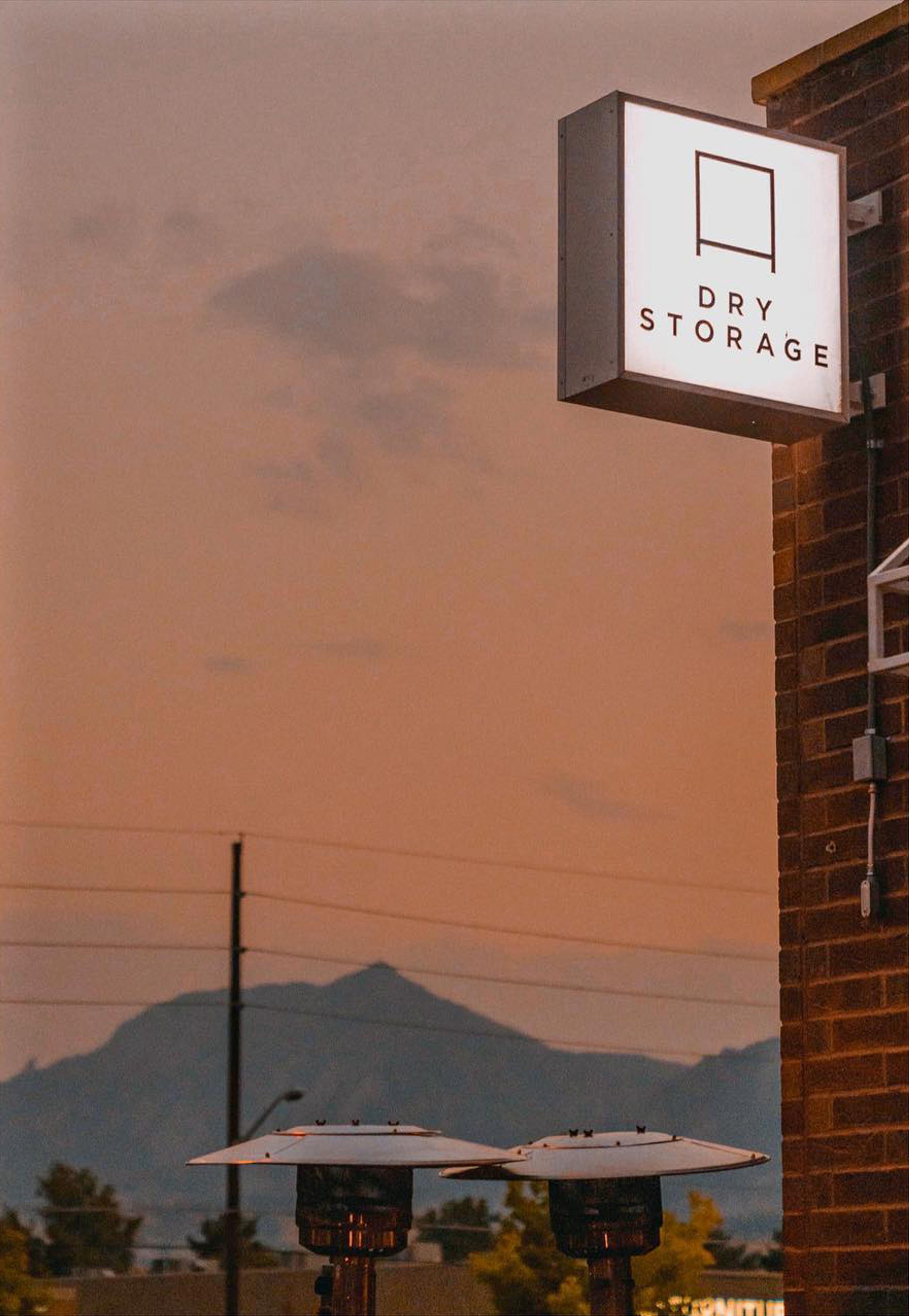 Exterior sign for Dry Storage cafe with sunset and mountains in background