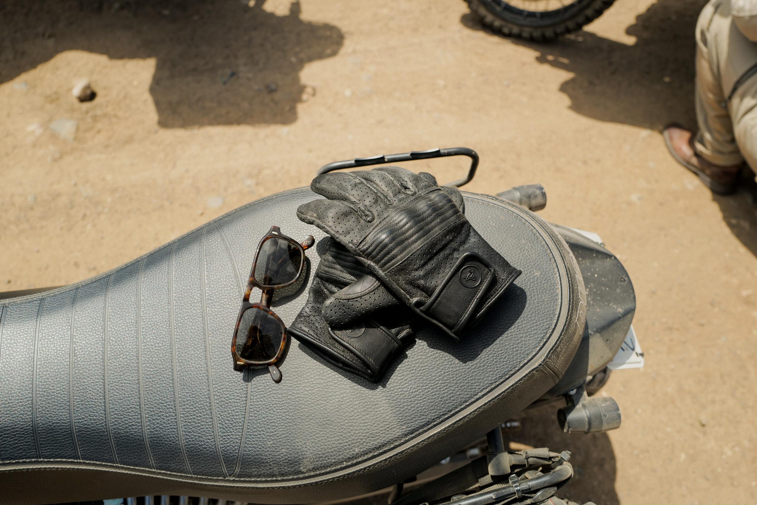 Top view of AETHER moto gloves and AETHER sunglasses on motorcycle seat