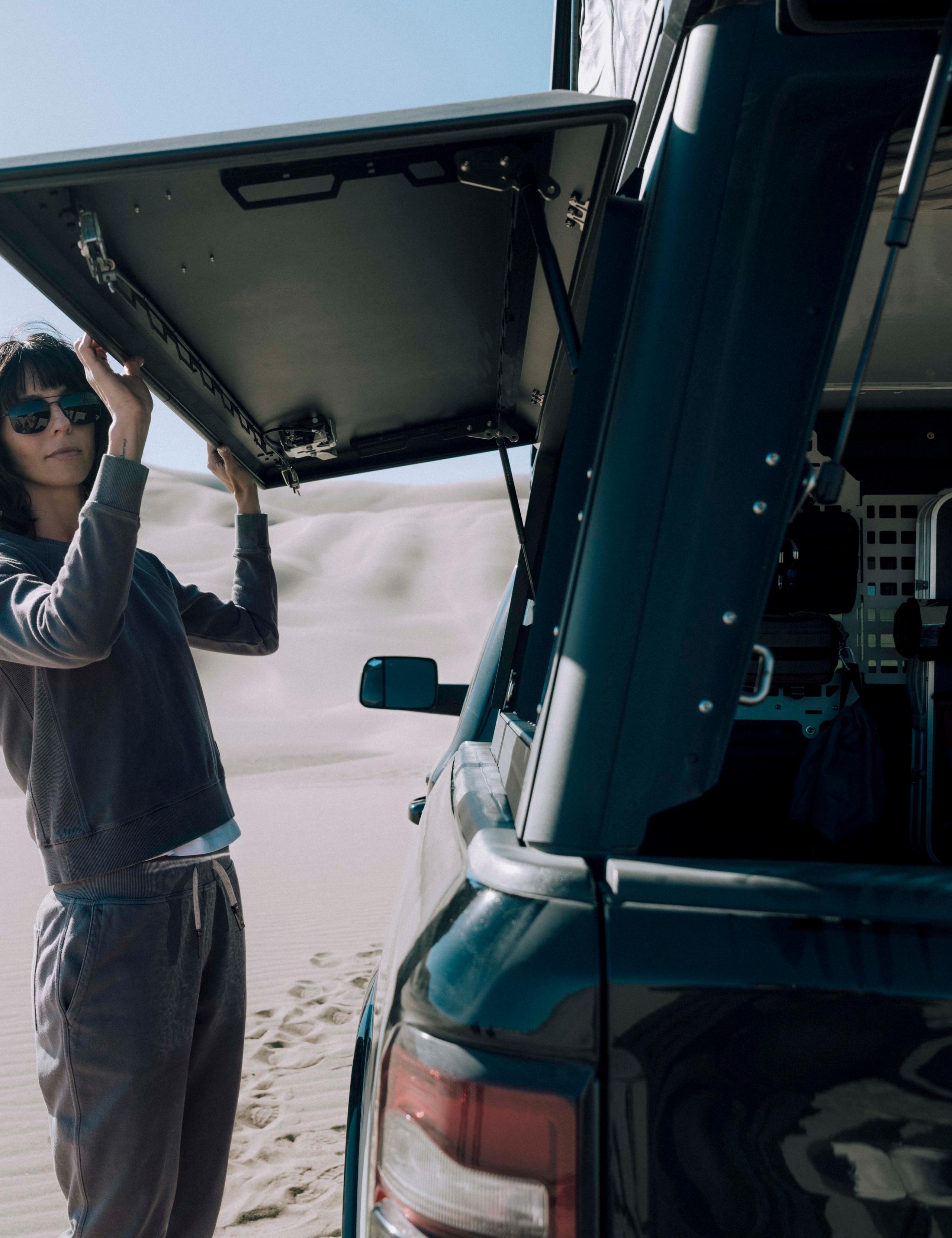 Woman in Solstice Lightweight Raglan Pullover loading her luggages into a camping car. 
