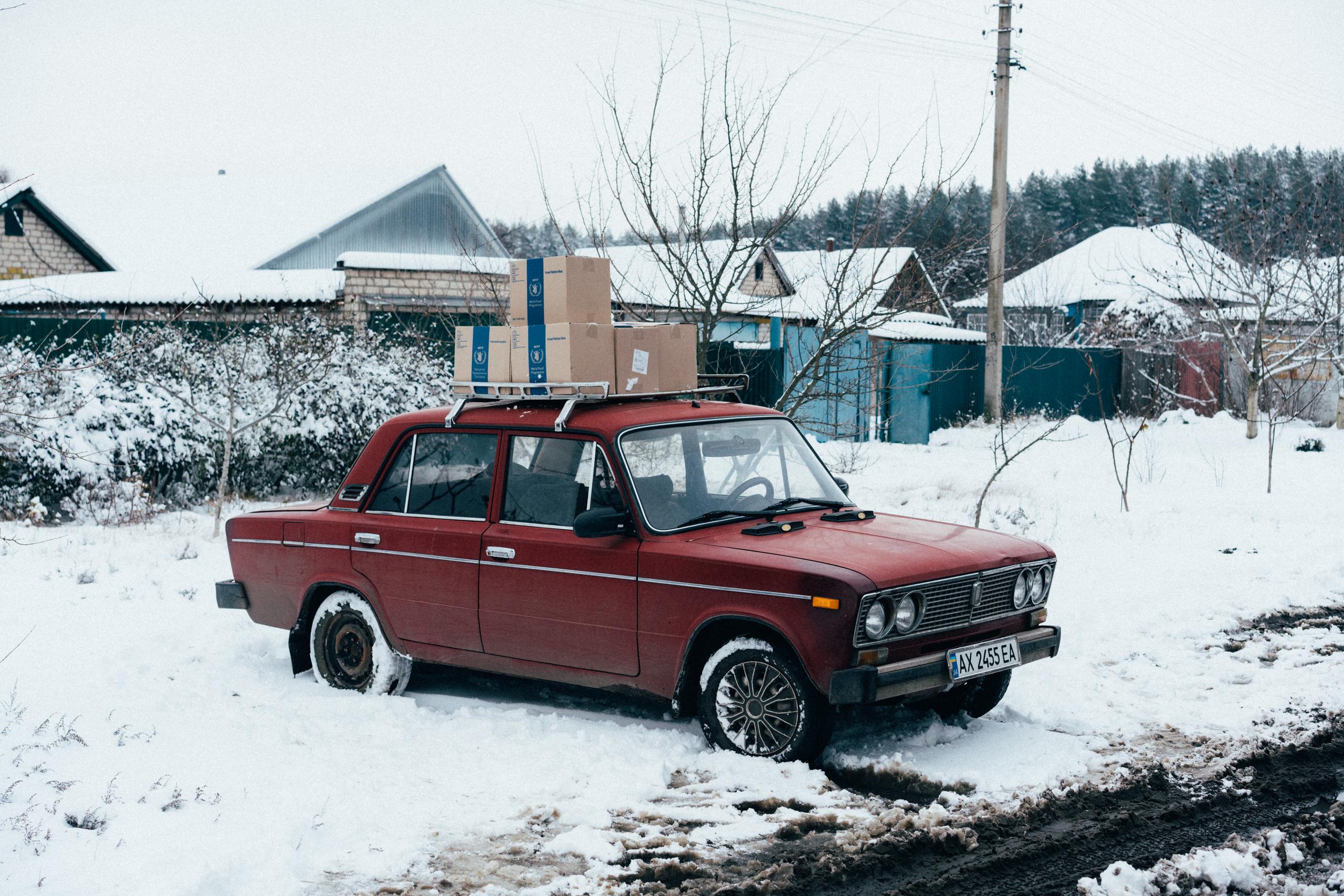 Old red car with boxes of food rations on top rack