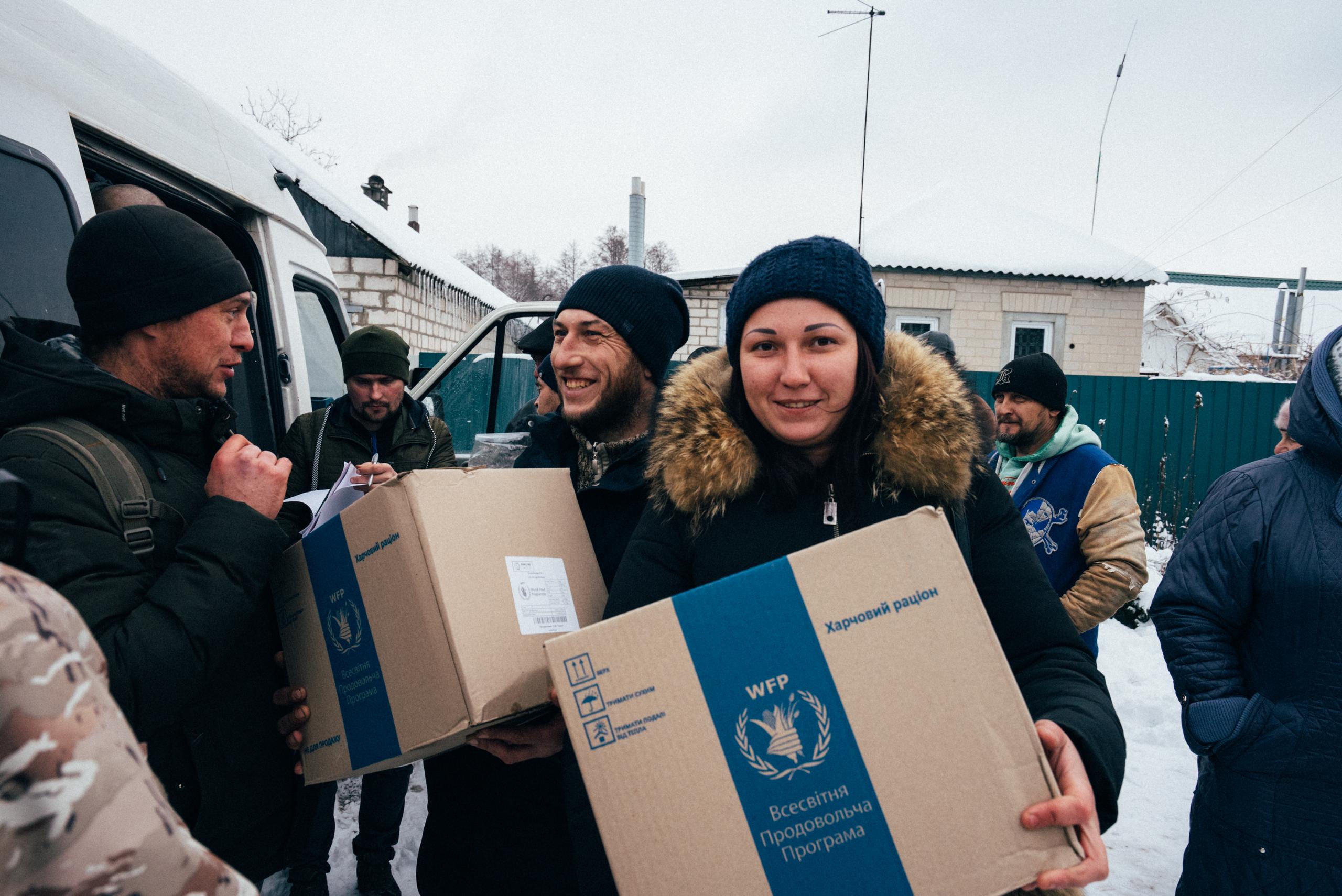 Man and woman holding a box of food rations smiling