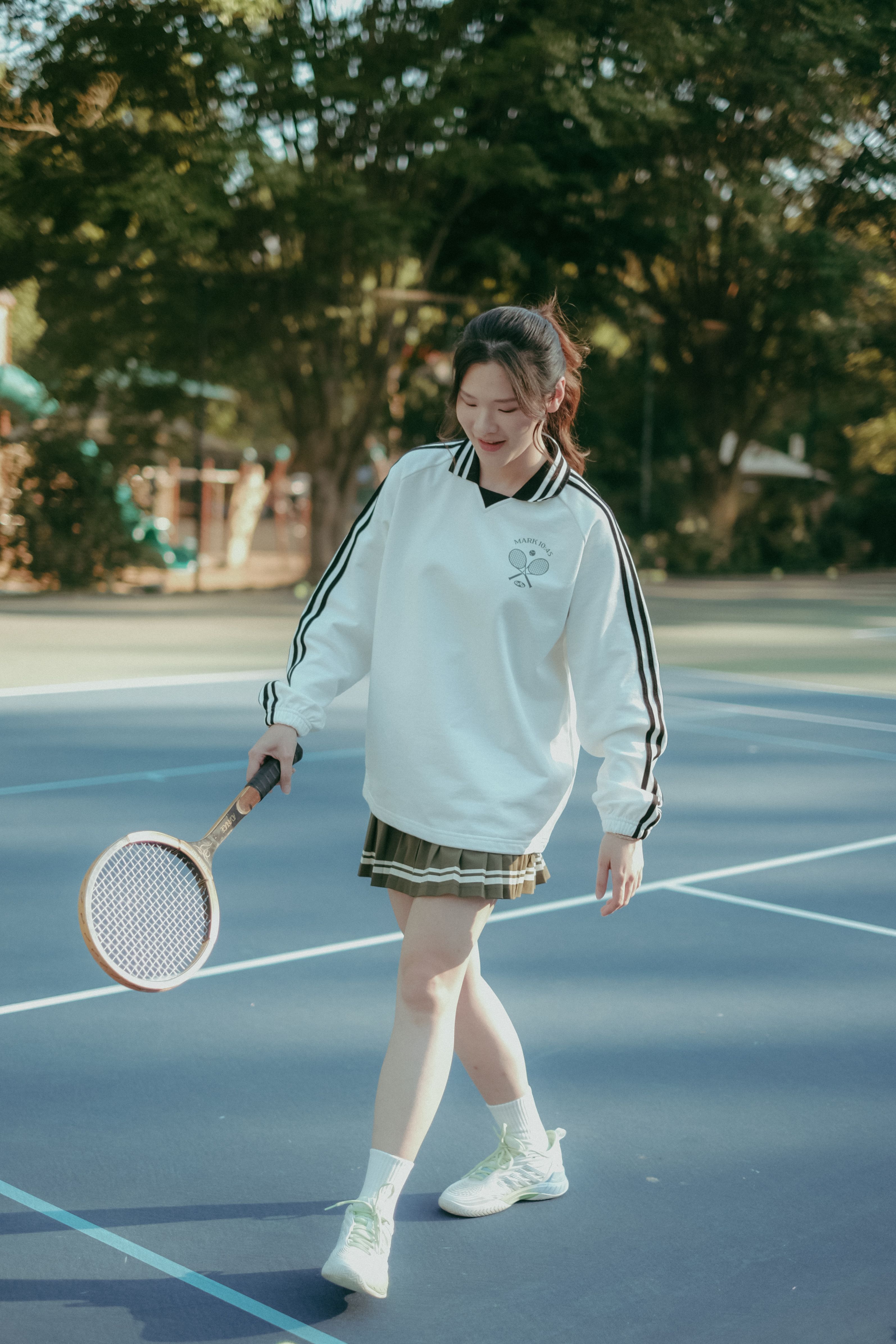 A girl wearing GFTD Jesus Came to Serve Tennis Pullover holding a wooden racket