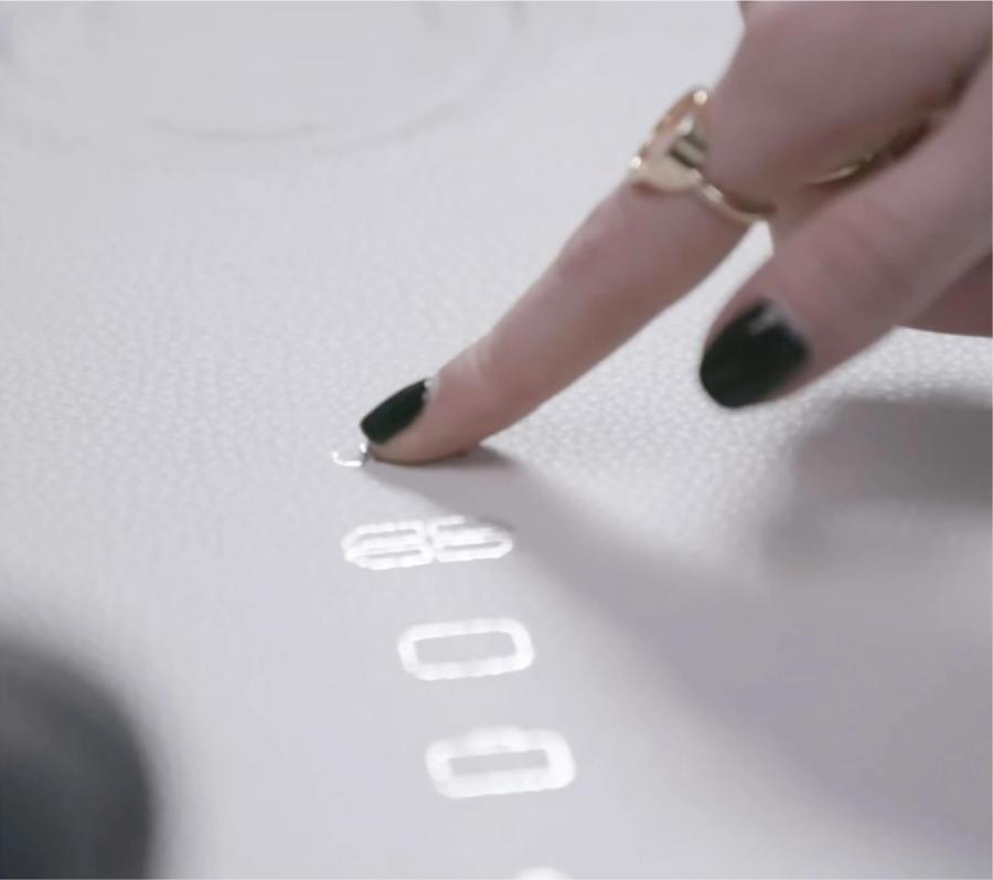 A finger on the light-up controls set into the table of Ford’s autonomous vehicle simulator