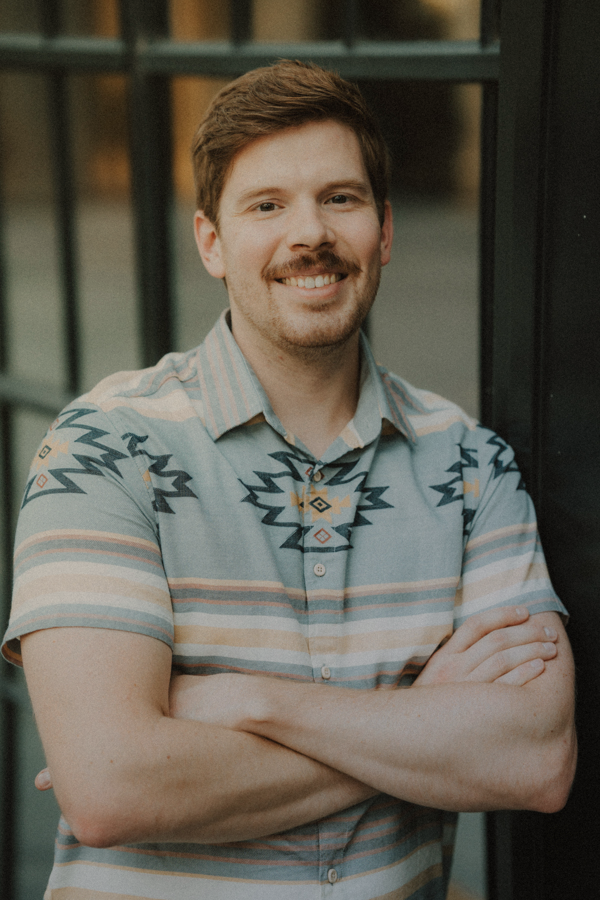 A photo of a man smiling with his arms crossed