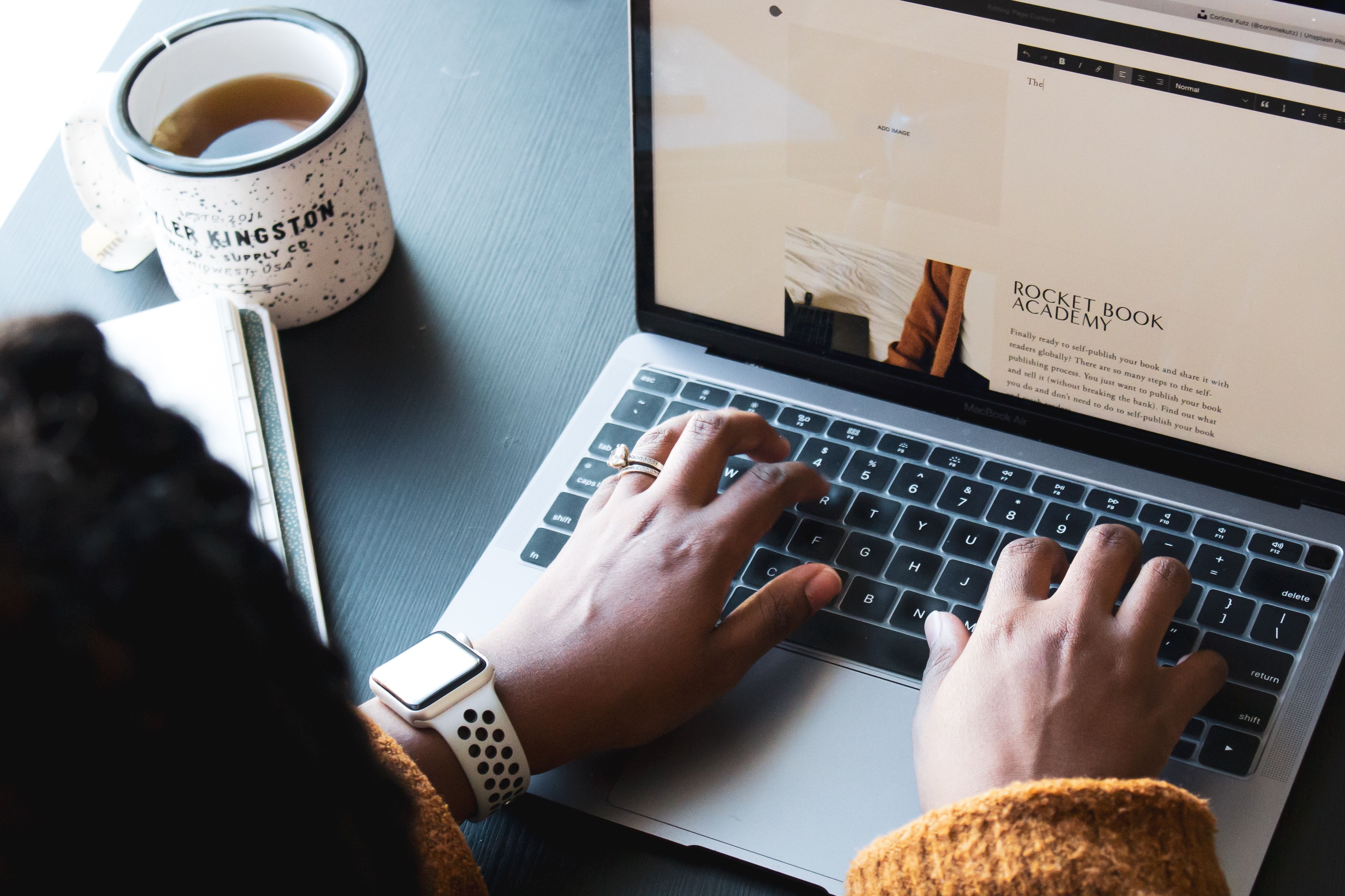 Overhead shot of woman typing on laptop that's rested on top of a table