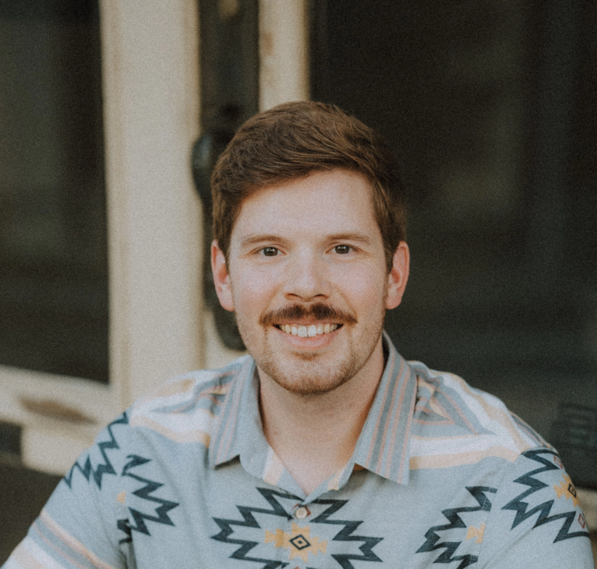 A man sitting down smiling at the camera