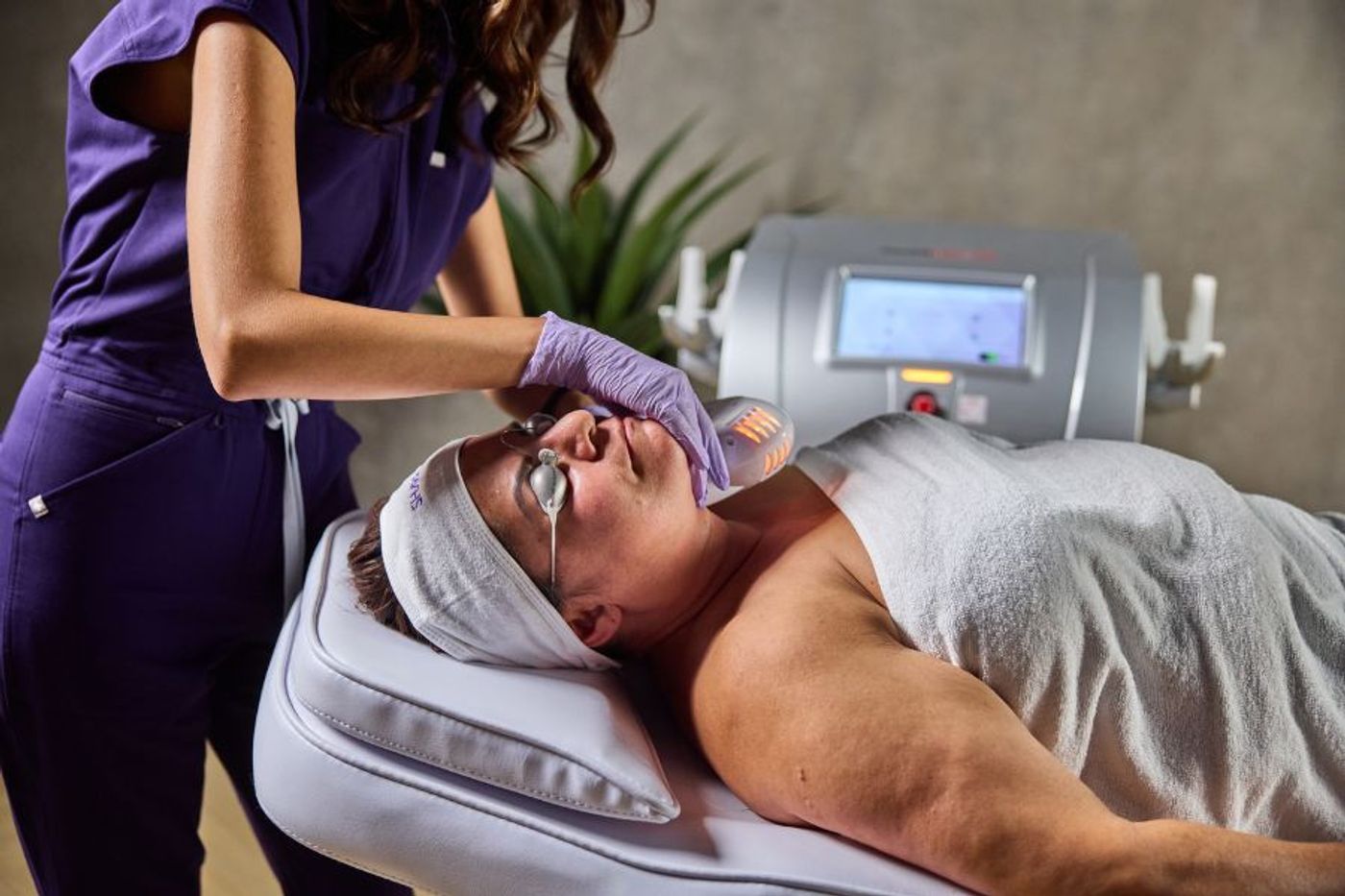 Clinician performing VermaDerm infrared skin tightening treatment on a client’s face using SharpLight technology