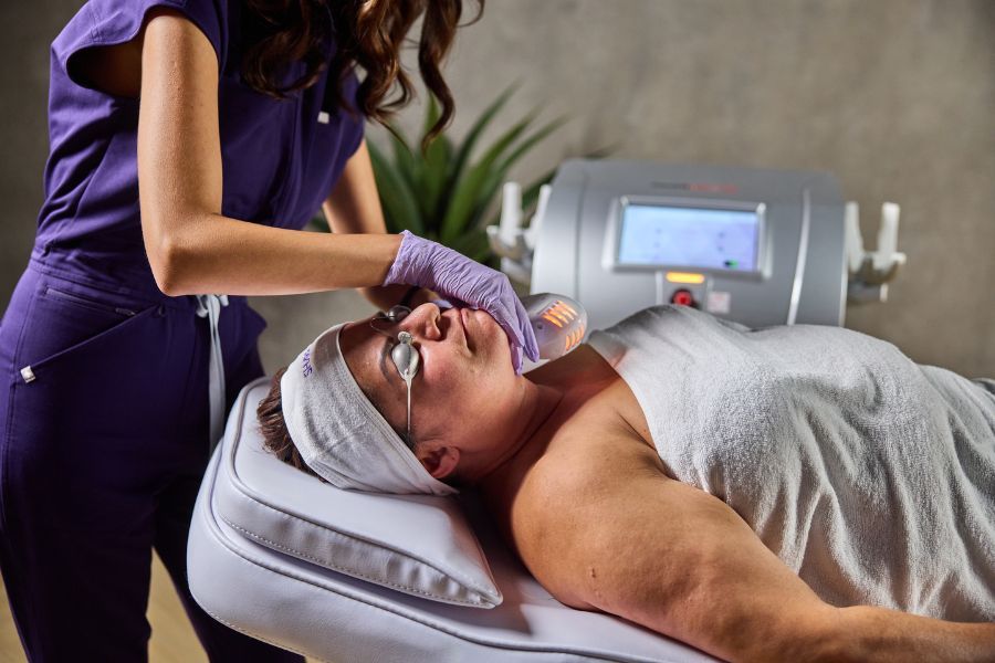 Clinician performing VermaDerm infrared skin tightening treatment on a client’s face using SharpLight technology