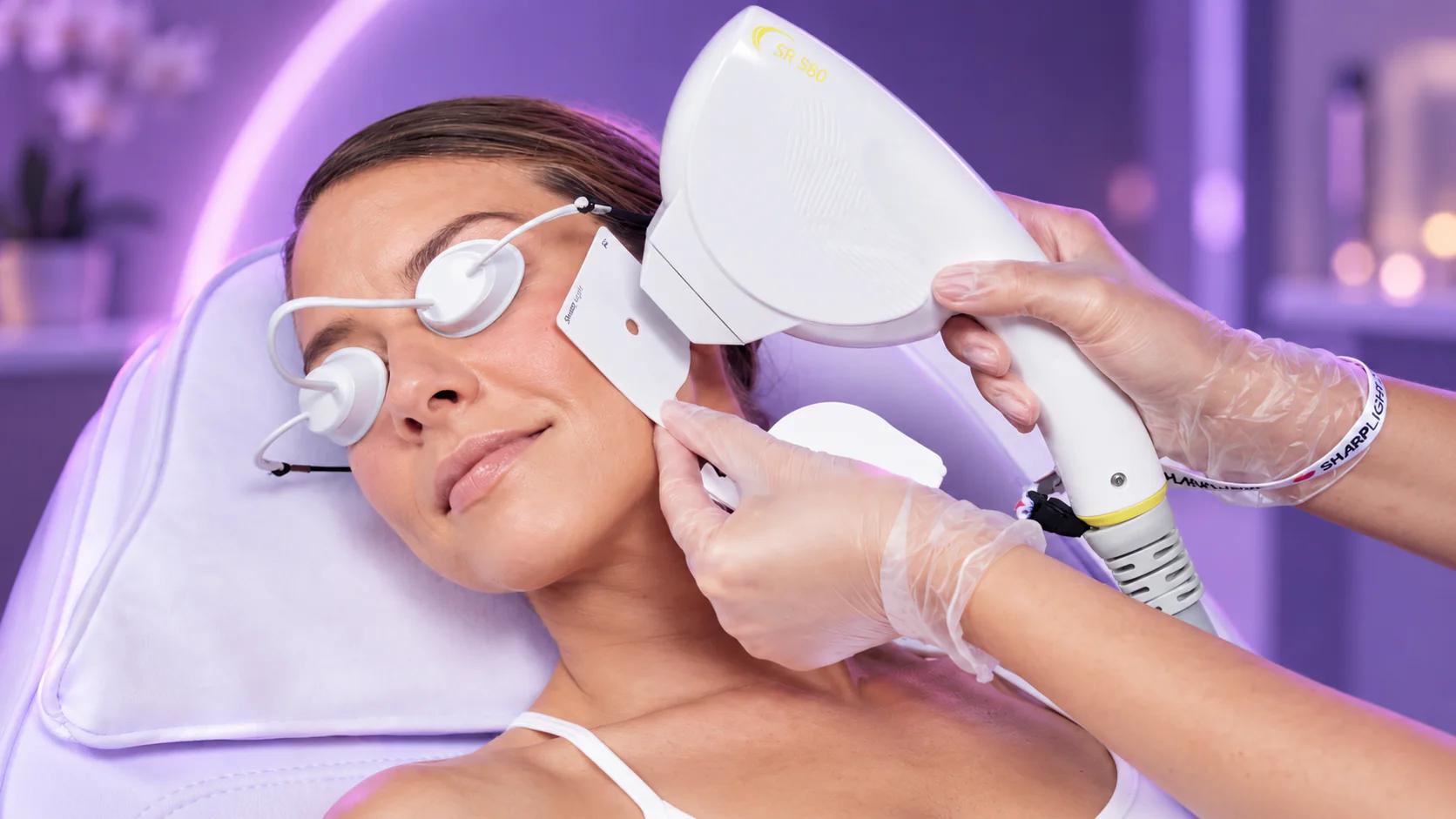Practitioner performing a SharpLight SR 580 skin rejuvenation treatment on a patient’s cheek while the patient wears protective eye shields