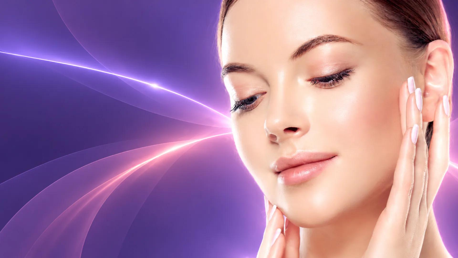 Woman touching her face against violet and pink light trails representing combined laser and injectable treatment planning.
