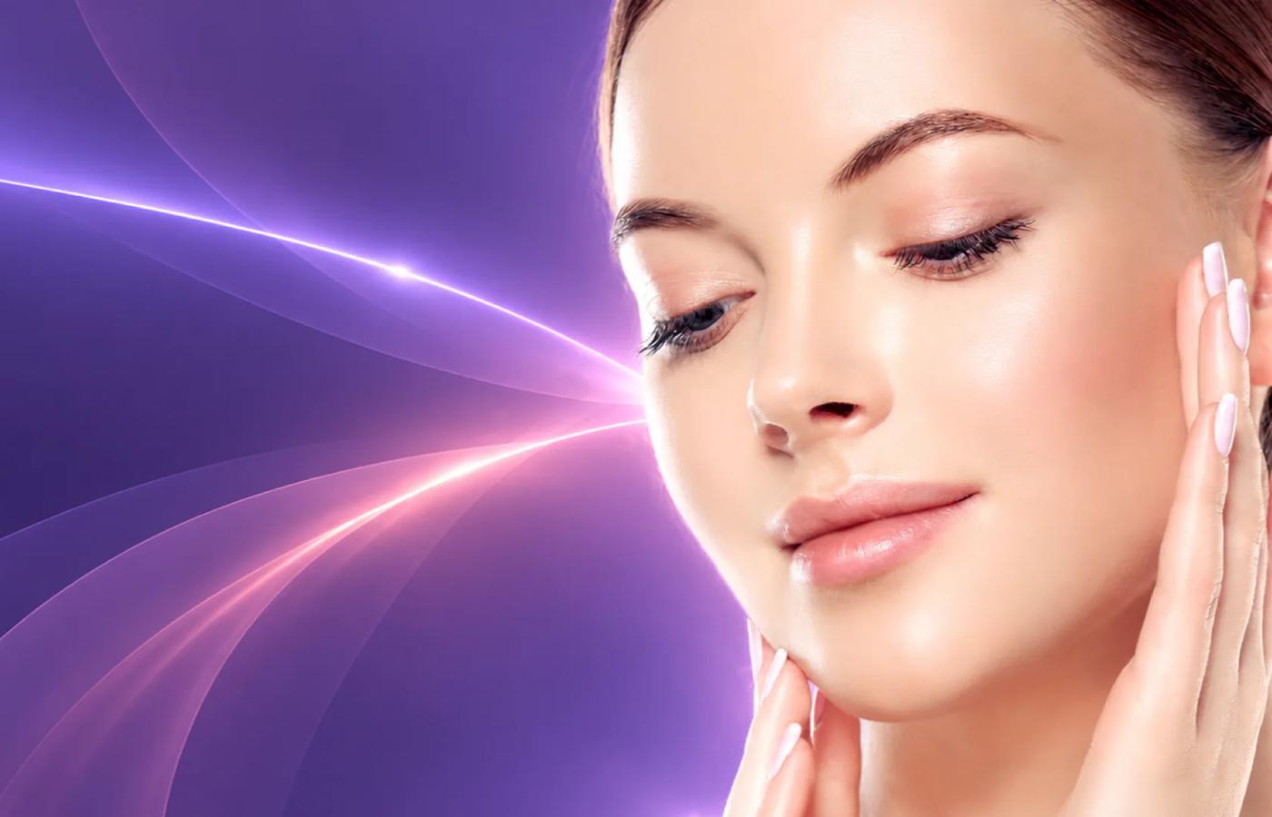 Woman touching her face against violet and pink light trails representing combined laser and injectable treatment planning.