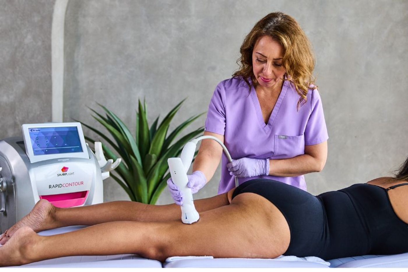 Clinician performing radio frequency body contouring on female client using SharpLight RapidContour device
