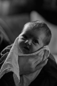 A portrait of a baby's chin resting in her mothers hand who is out-of-frame.