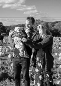 Me, holding my daughter while my wife clicks her fingers trying to get her to smile for a photo. We're stood in a pumpkin field.