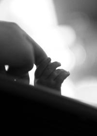 A baby's hand reaching up to grab a finger.