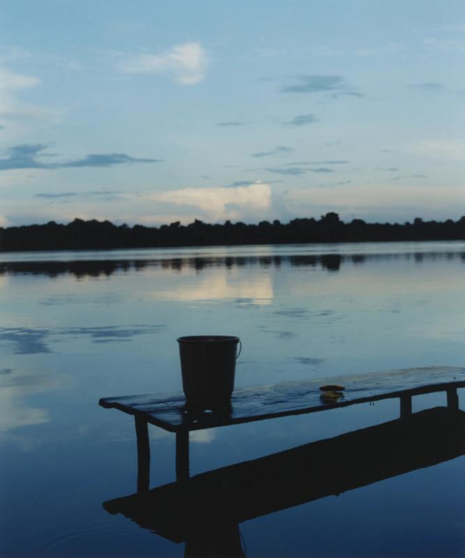 a bucket sits on a dock overlooking a lake