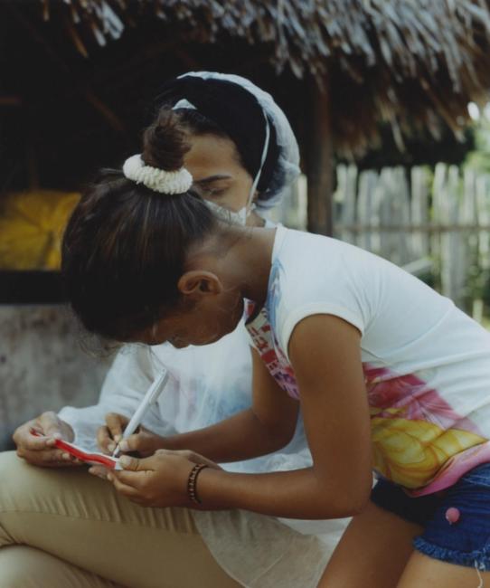 a woman and a girl are writing on a piece of paper .