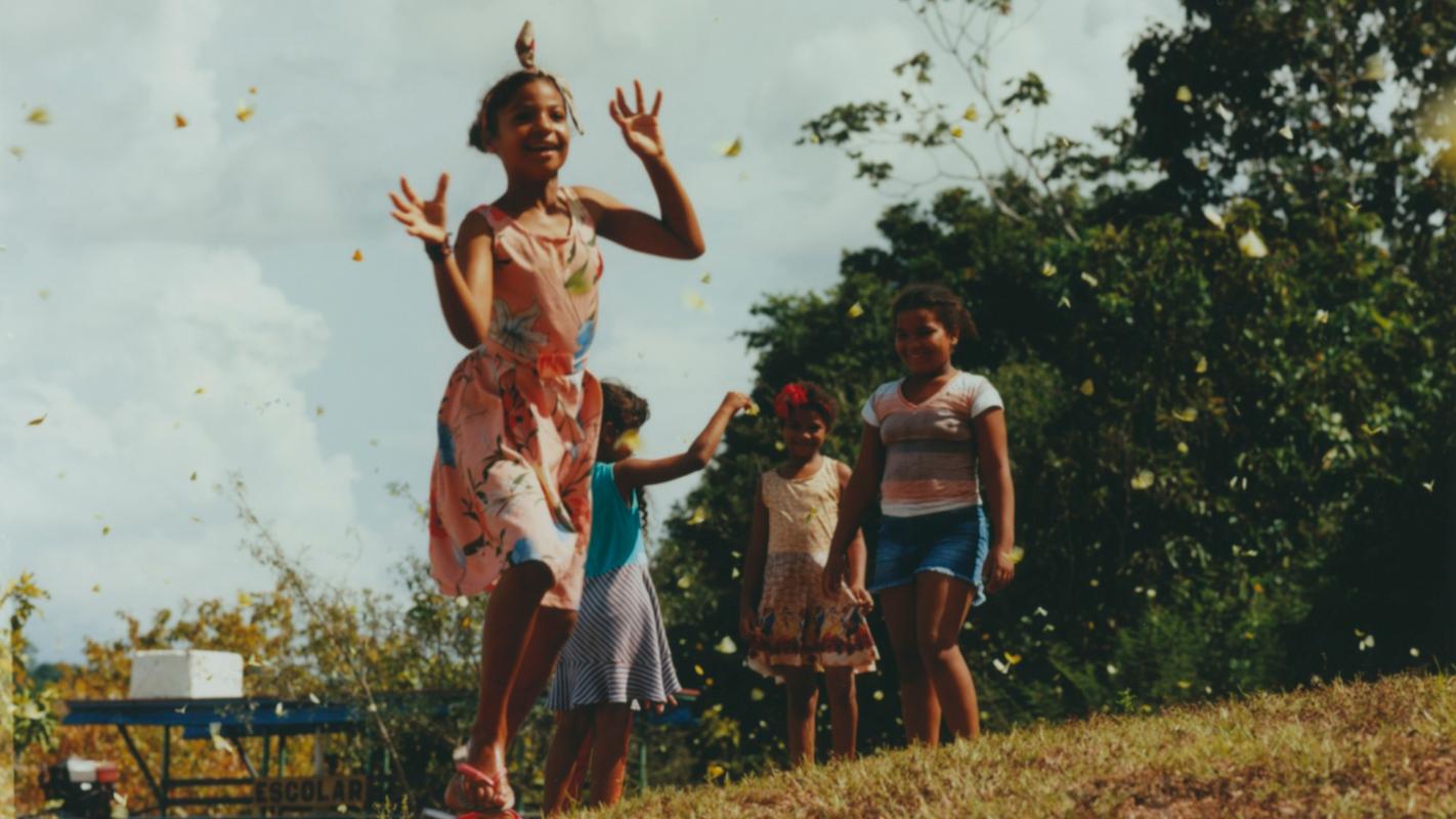 a group of young girls are standing on top of a grass covered hill .