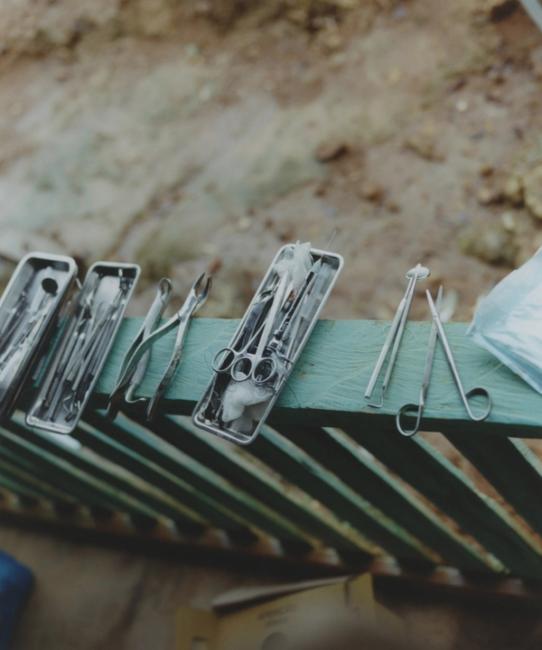 a row of surgical instruments on a green railing