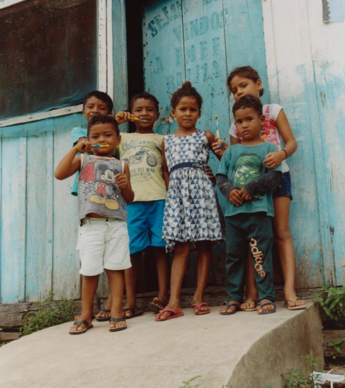 a group of children brushing their teeth in front of a blue door