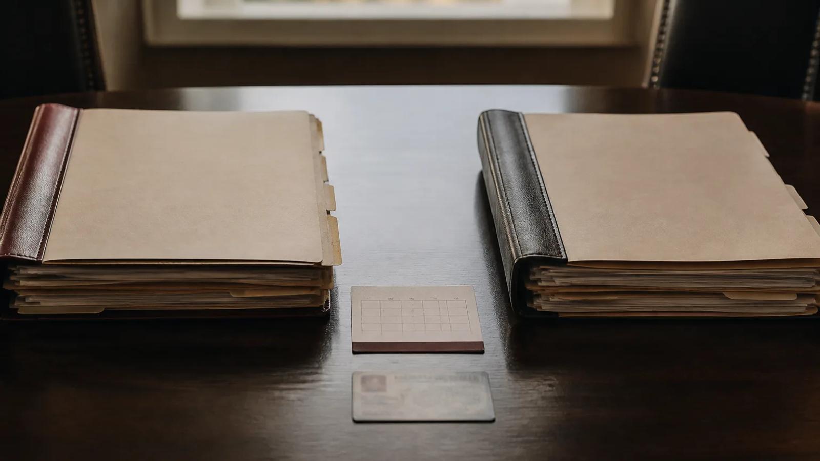 Two anonymous DUI case folders with a calendar card and license-sized document between them