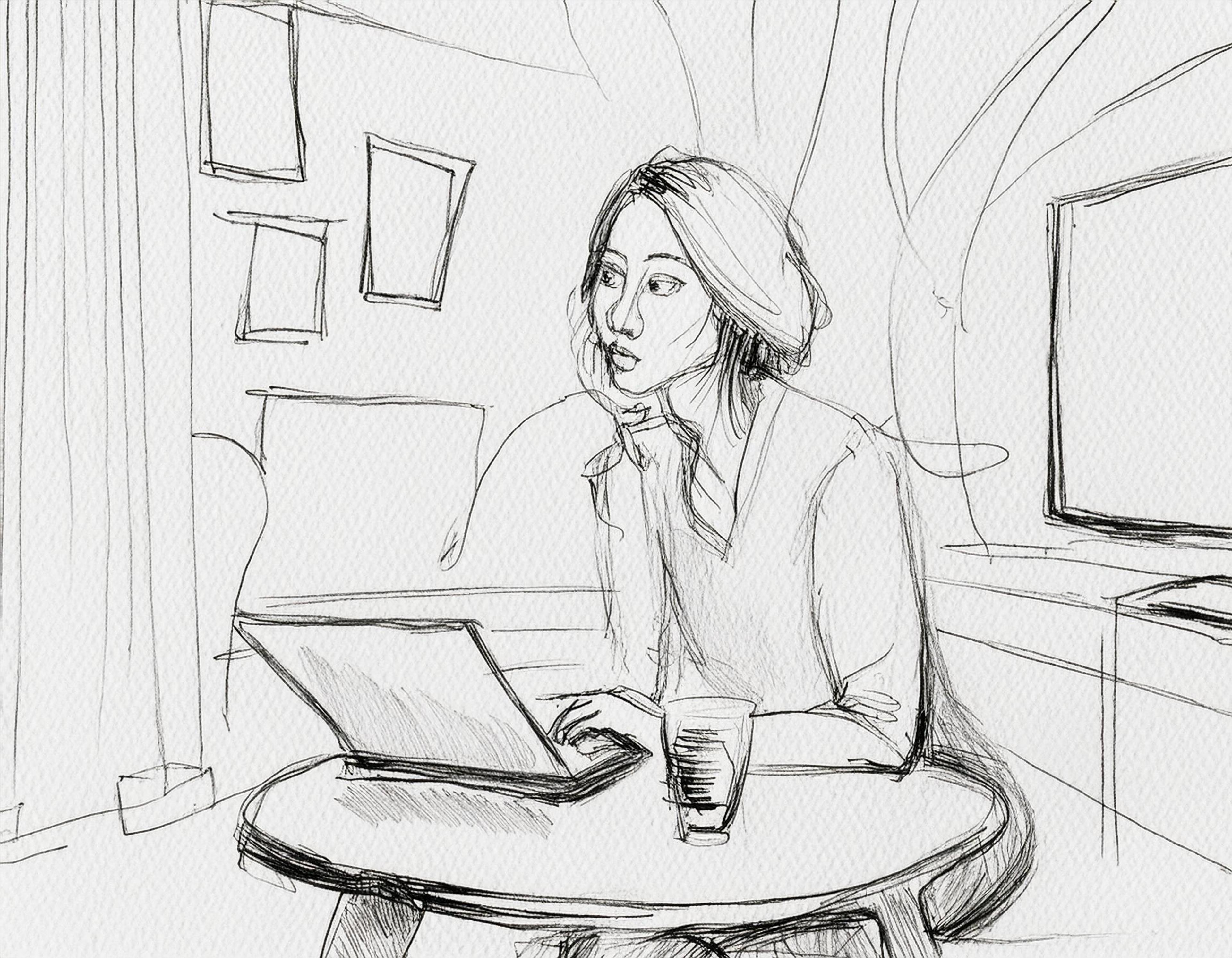 En dame sitter foran en laptop hjemme og ser opp