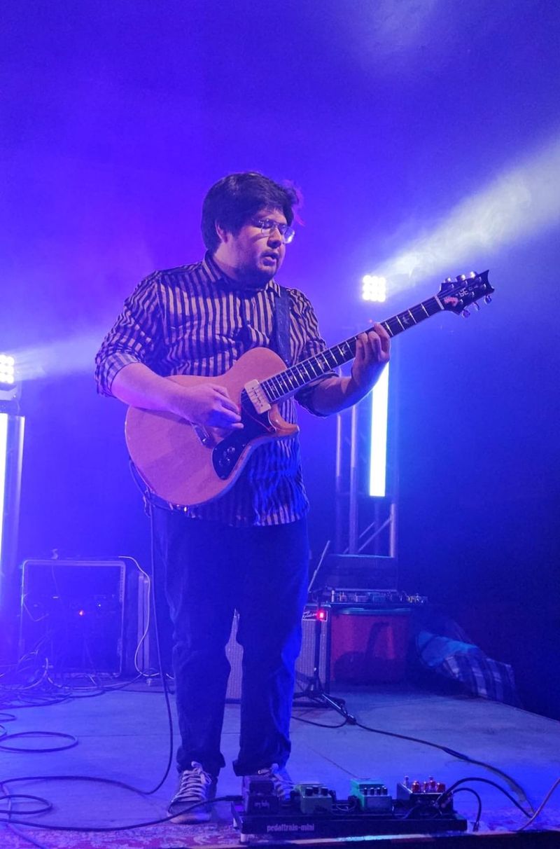Jorge Luis tocando la guitarra en el escenario con luces de color azul