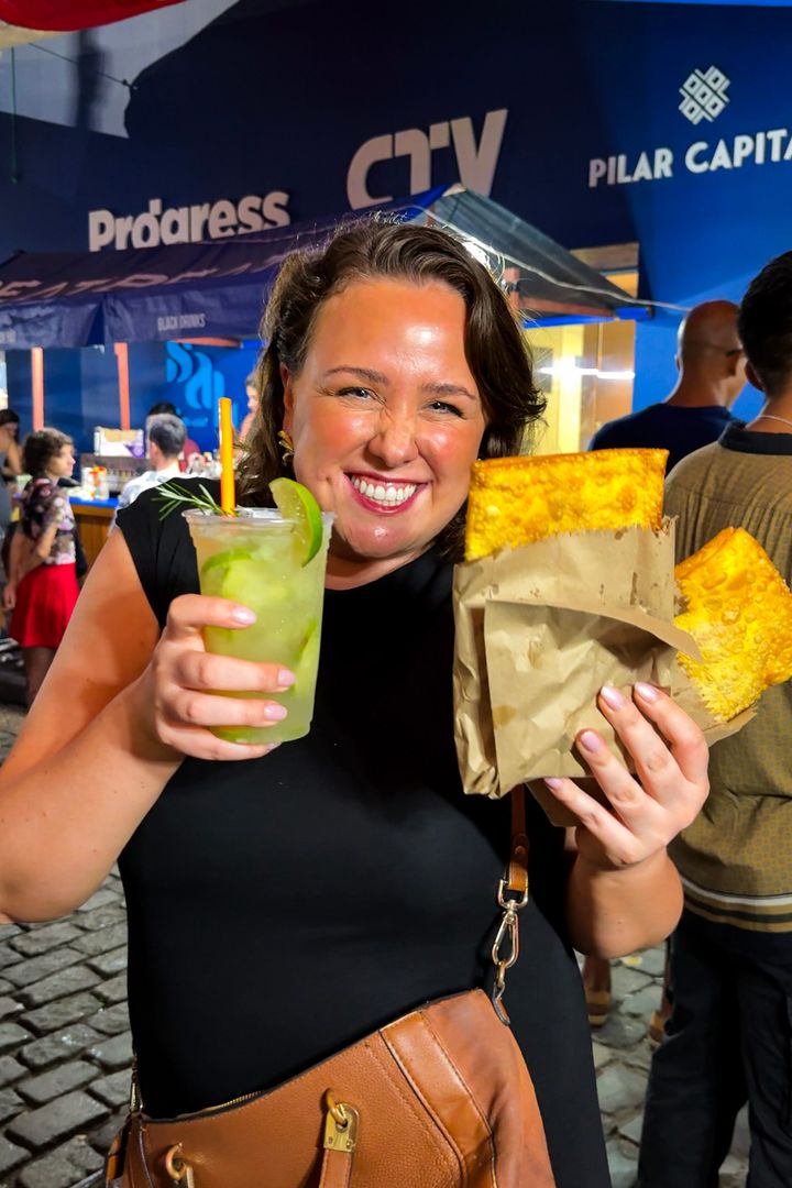 woman holding a caipirinha and pastels at pedro do sal in rio de janeiro, brazil