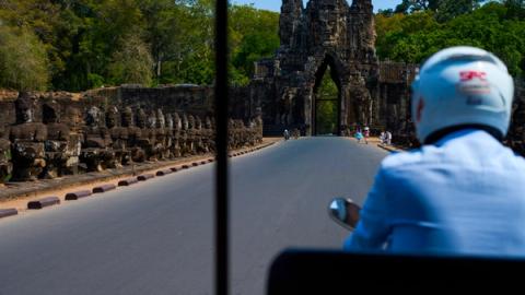tuk tuk driver entering angkor wat on his tuk tuk in siem reap, cambodia