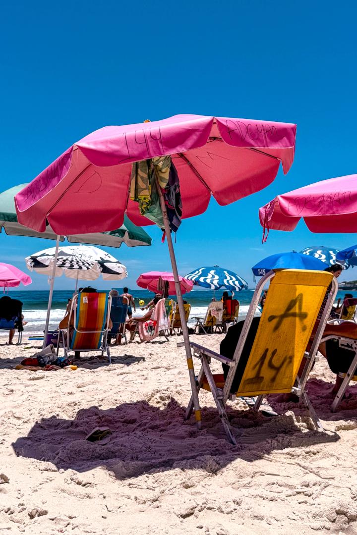 a pink umbrella and beach chairs on copacobana beach in Rio de Janeiro, brazil