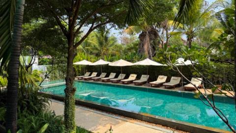 pool and chairs in a garden at khmer house hotel in siem reap, cambodia