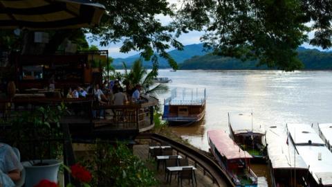 view of the mekong river aling luang prabang in laos with restaurants full of people on the side