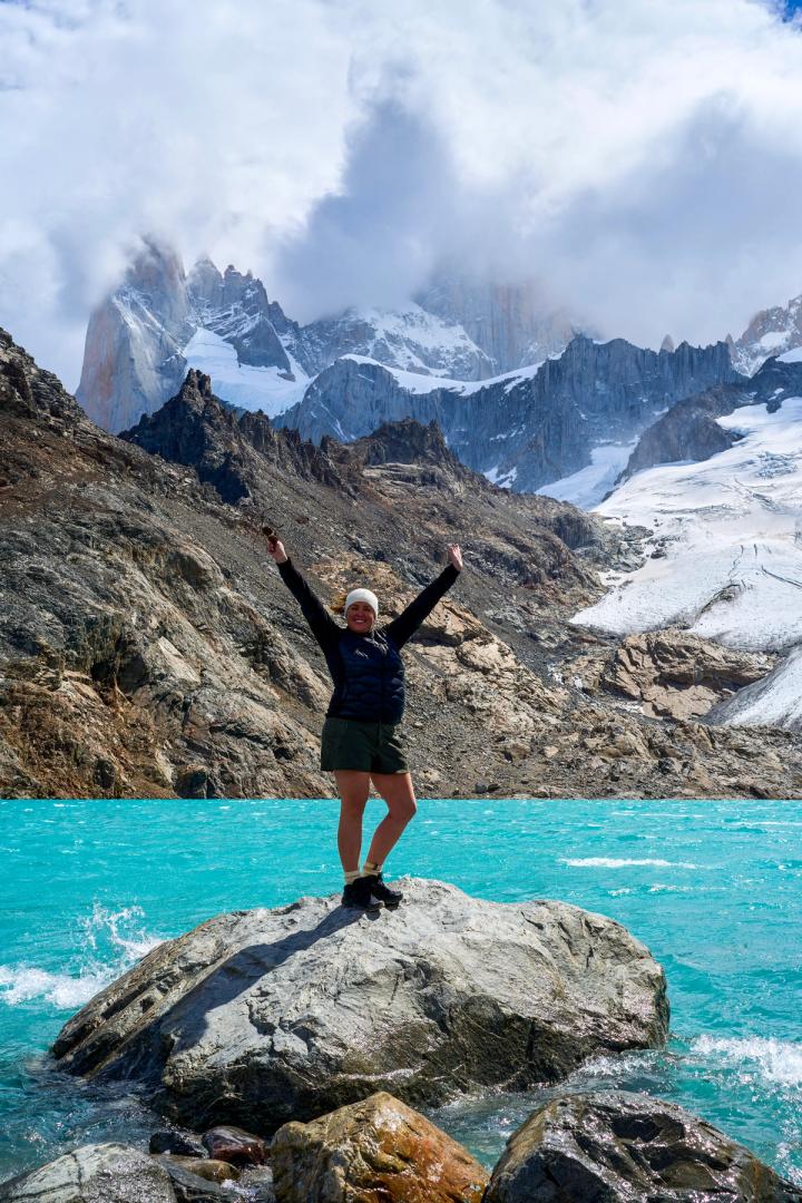 woman standing at a rock in front of laguna de los tres in el chalten, argentina