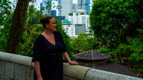 woman in black dress looks out on the view of Singapore from fort canning park, Singapore