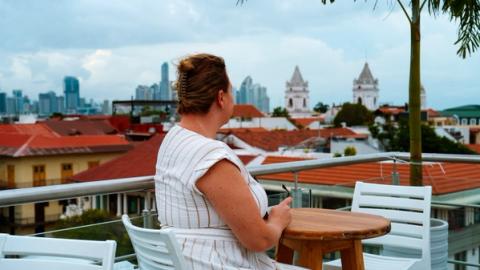 a woman drinking a glass of wine while looking over panama city