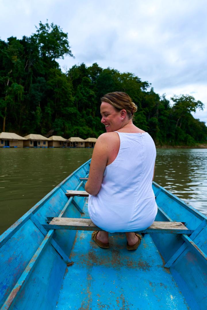 woman sitting in a blue wooden boat on the river in luang prabang, laos