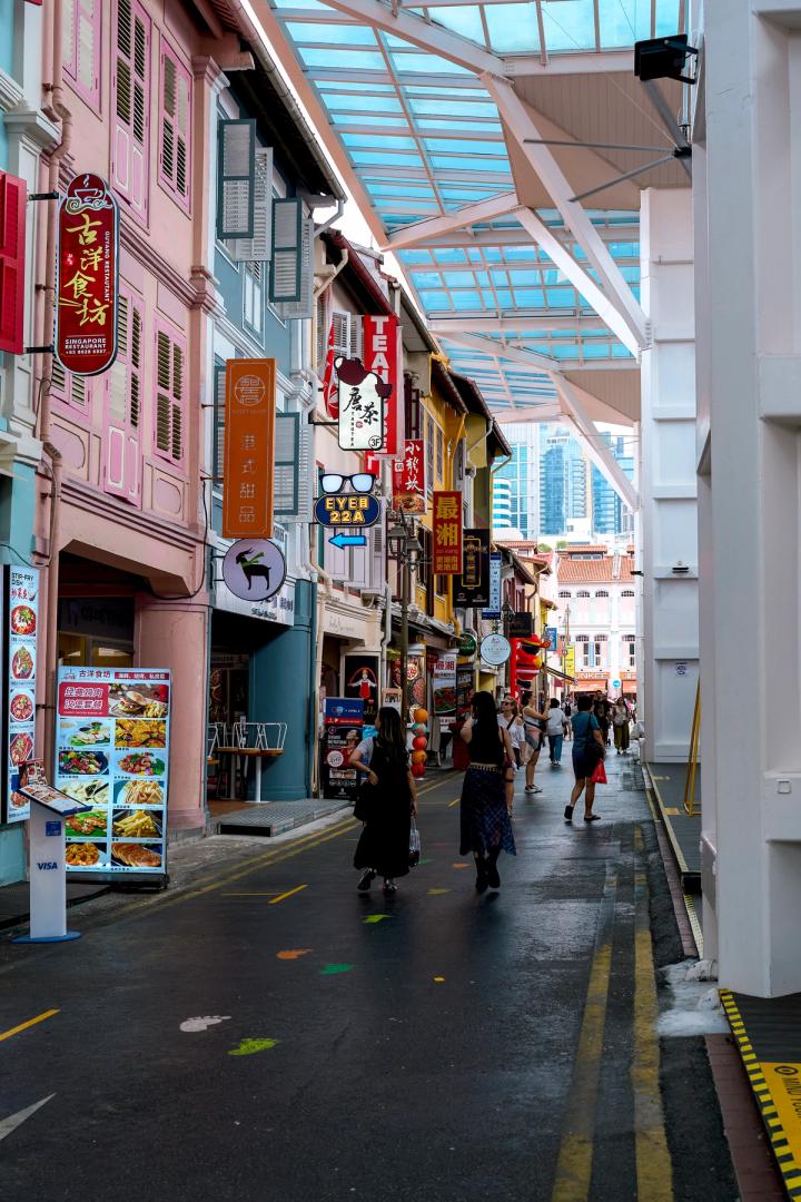 people walking around the colourful buildings in chinatown, Singapore
