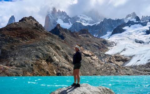 woman standing on a rock in front of laguna de los tres in el chalten, argentina