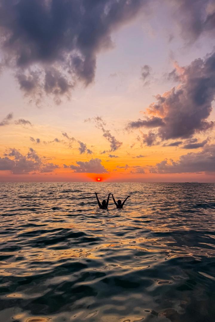 two women swimming in the water at sunset in Koh Lanta, thailand