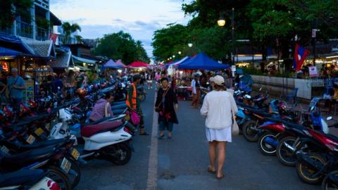 woman walking through the old town in luang prabang, laos
