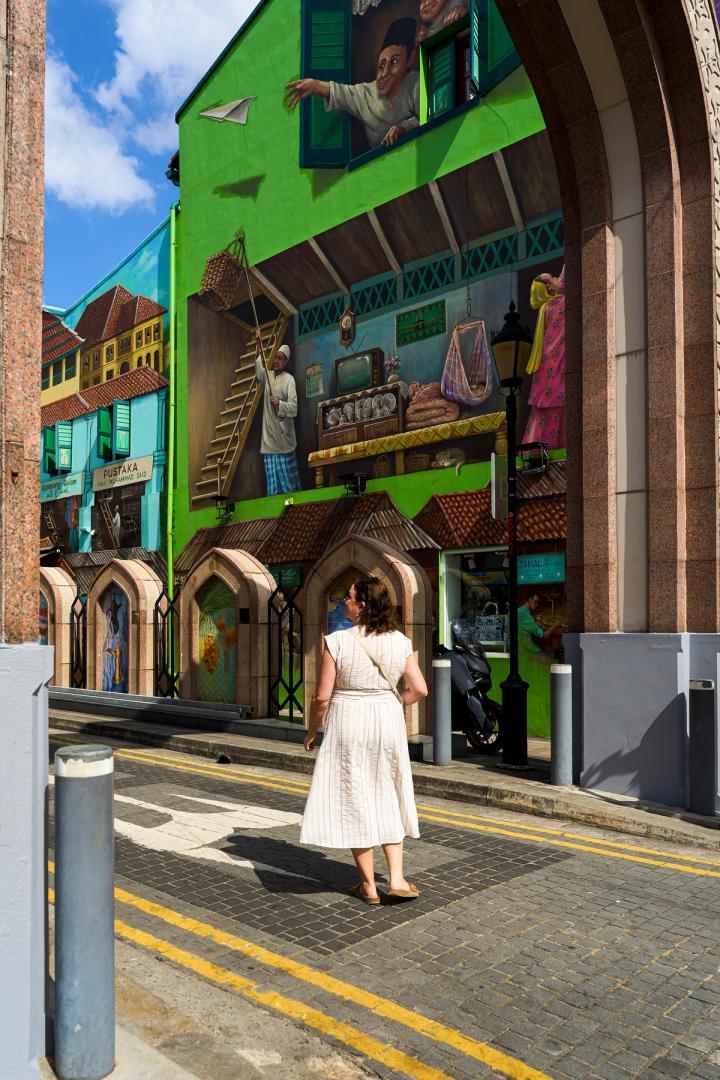 woman walking in a white dress in the green streets of Muscat street, Singapore