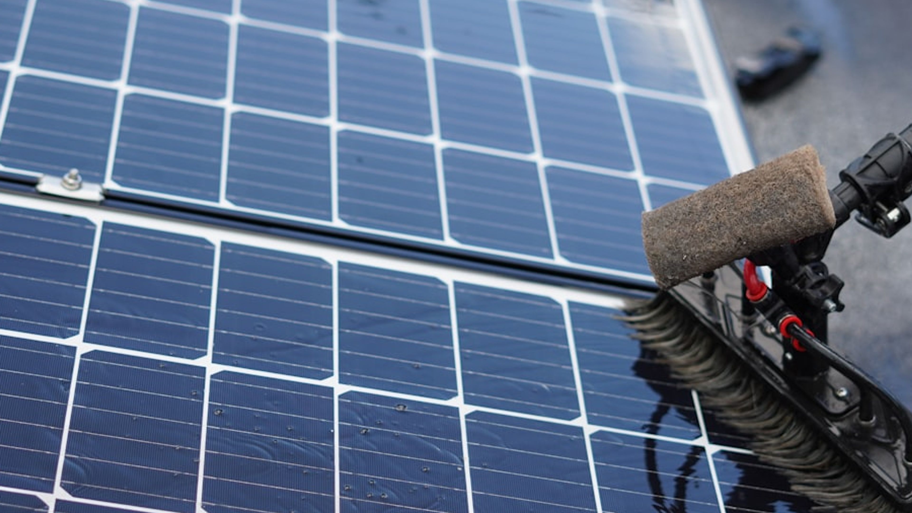 Escova de limpeza removendo sujeira de módulos fotovoltaicos molhados.