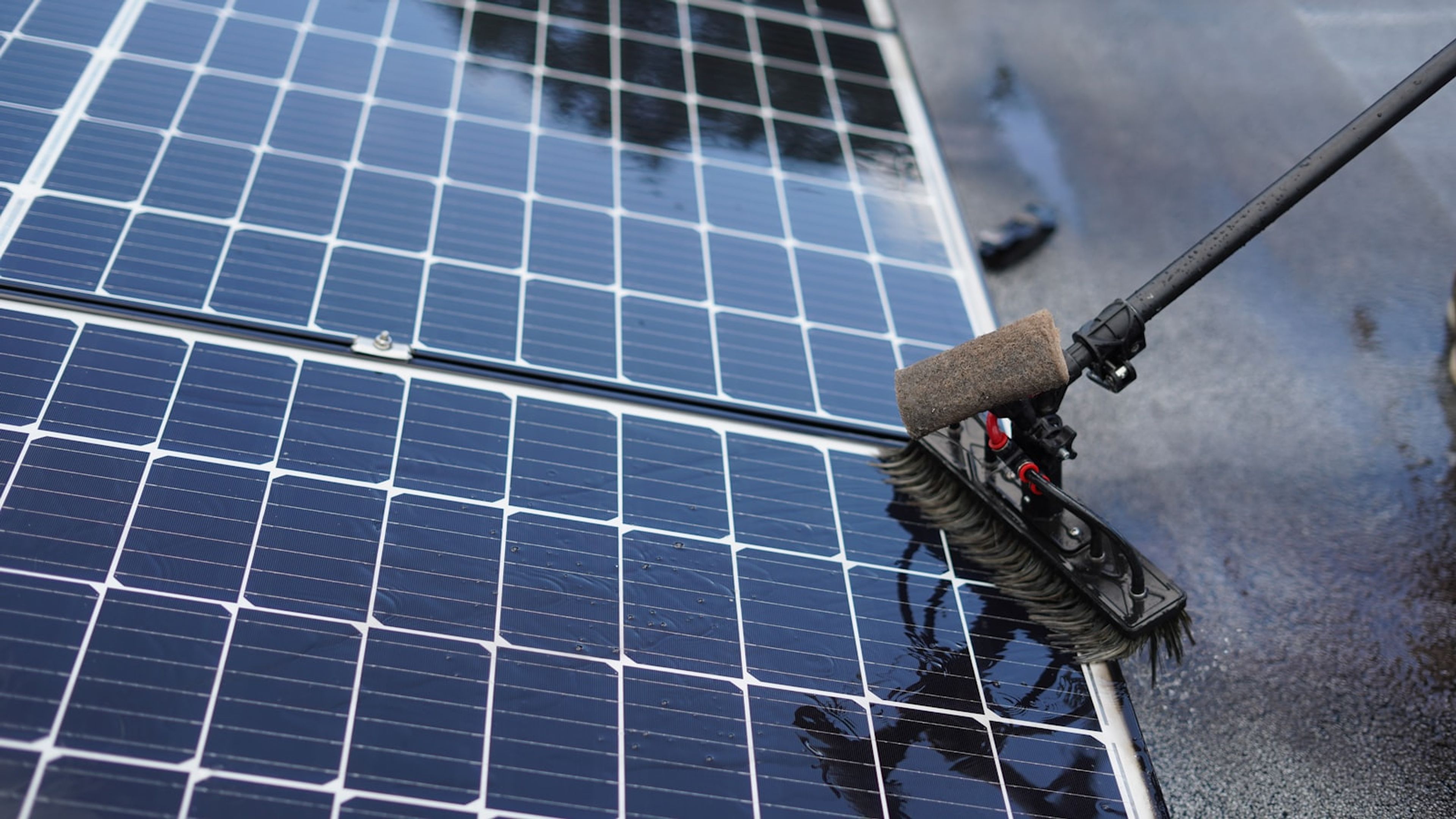 Escova de limpeza removendo sujeira de módulos fotovoltaicos molhados.