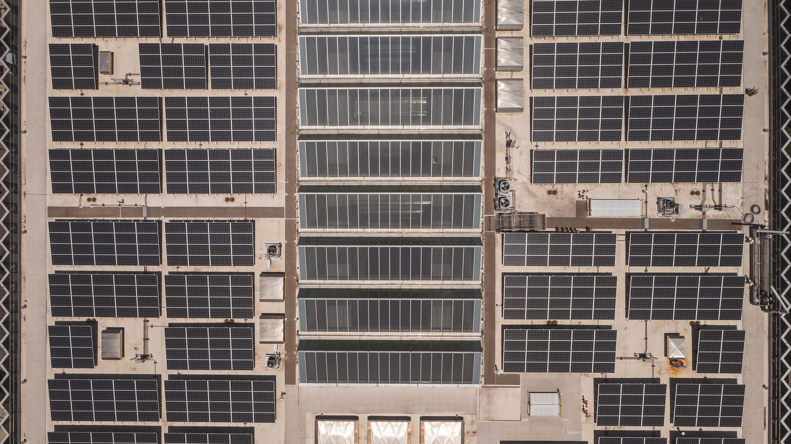Vista aérea de telhado comercial coberto por módulos fotovoltaicos.