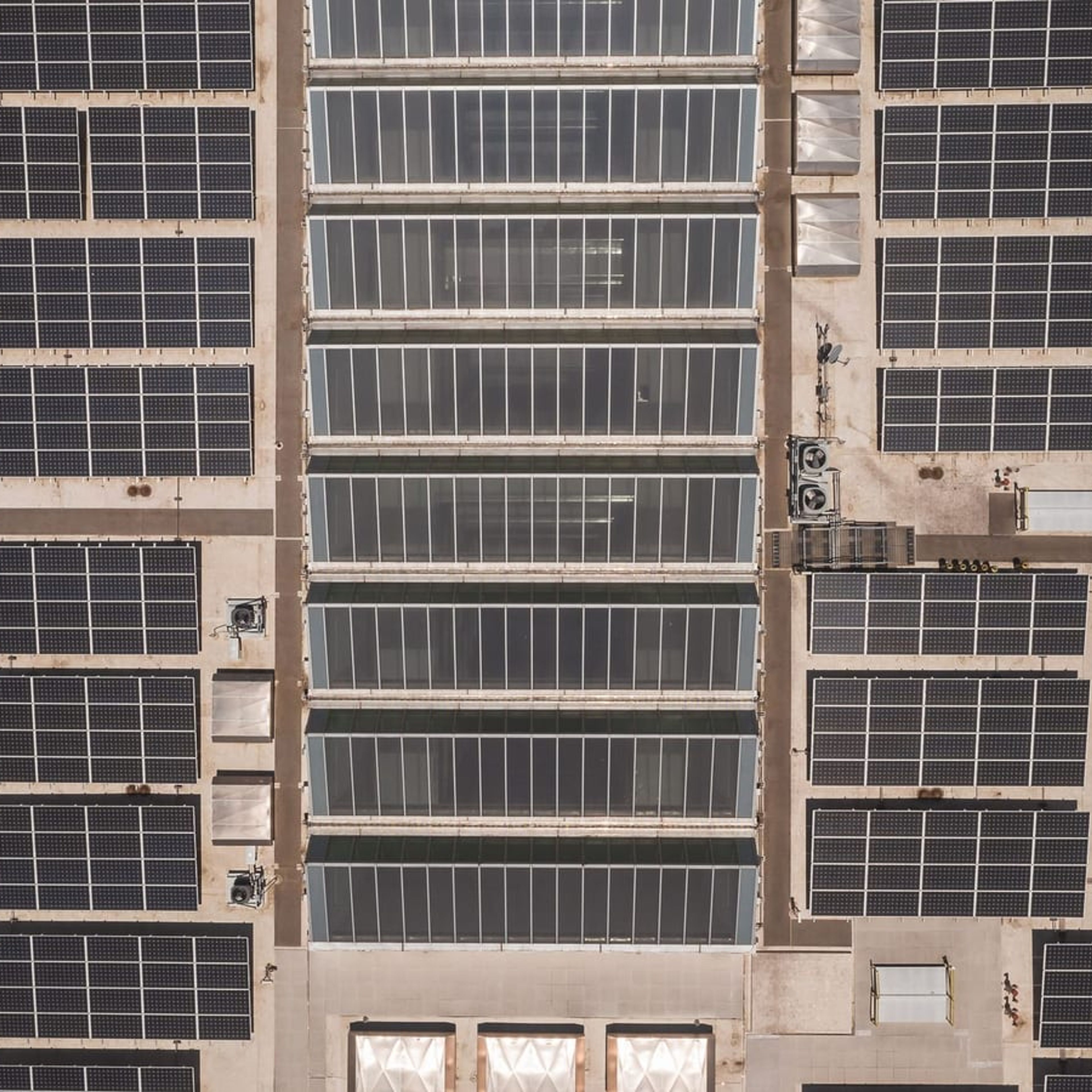 Vista aérea de telhado comercial coberto por módulos fotovoltaicos.