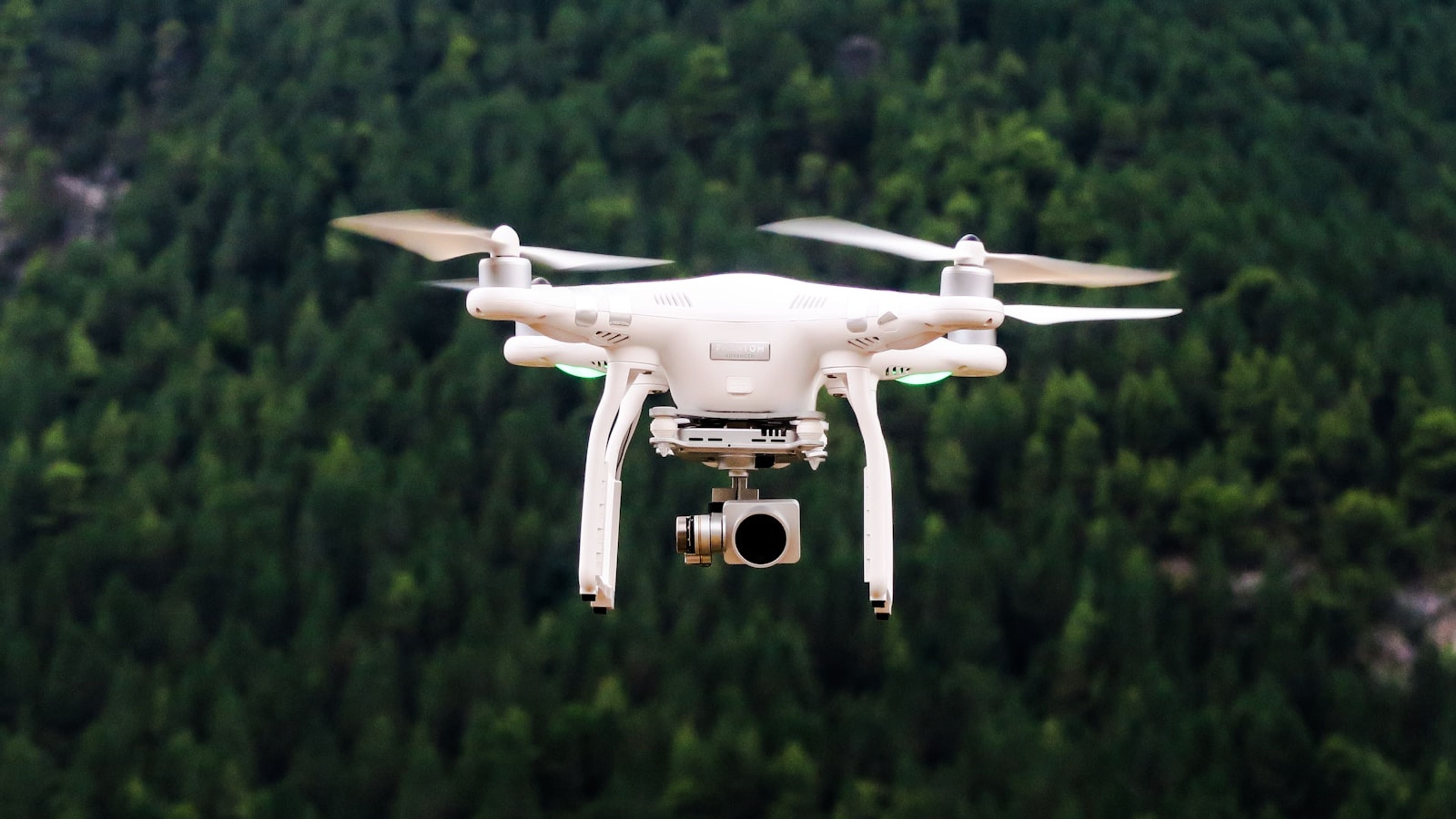 Drone de inspeção com câmera sobrevoando área verde.