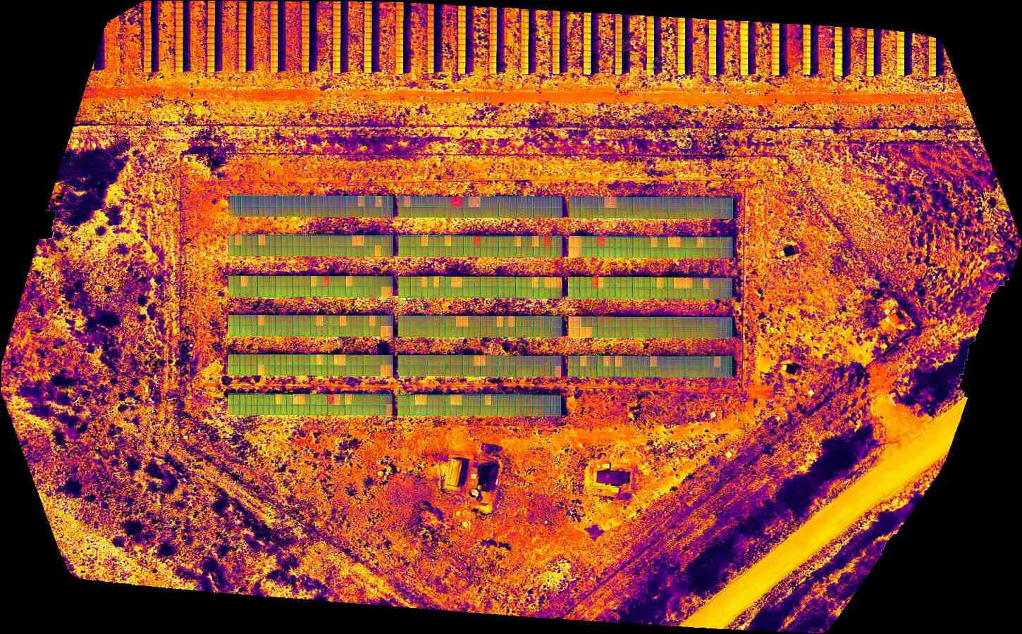 Imagem termografica aerea de usina solar com anomalias destacadas por cores.